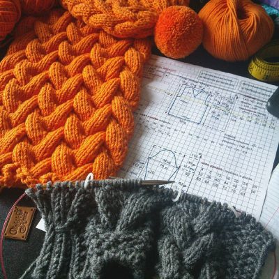 Оранжевый снуд с крупными косами, серое полотно на спицах и нарисованная от руки схема узора