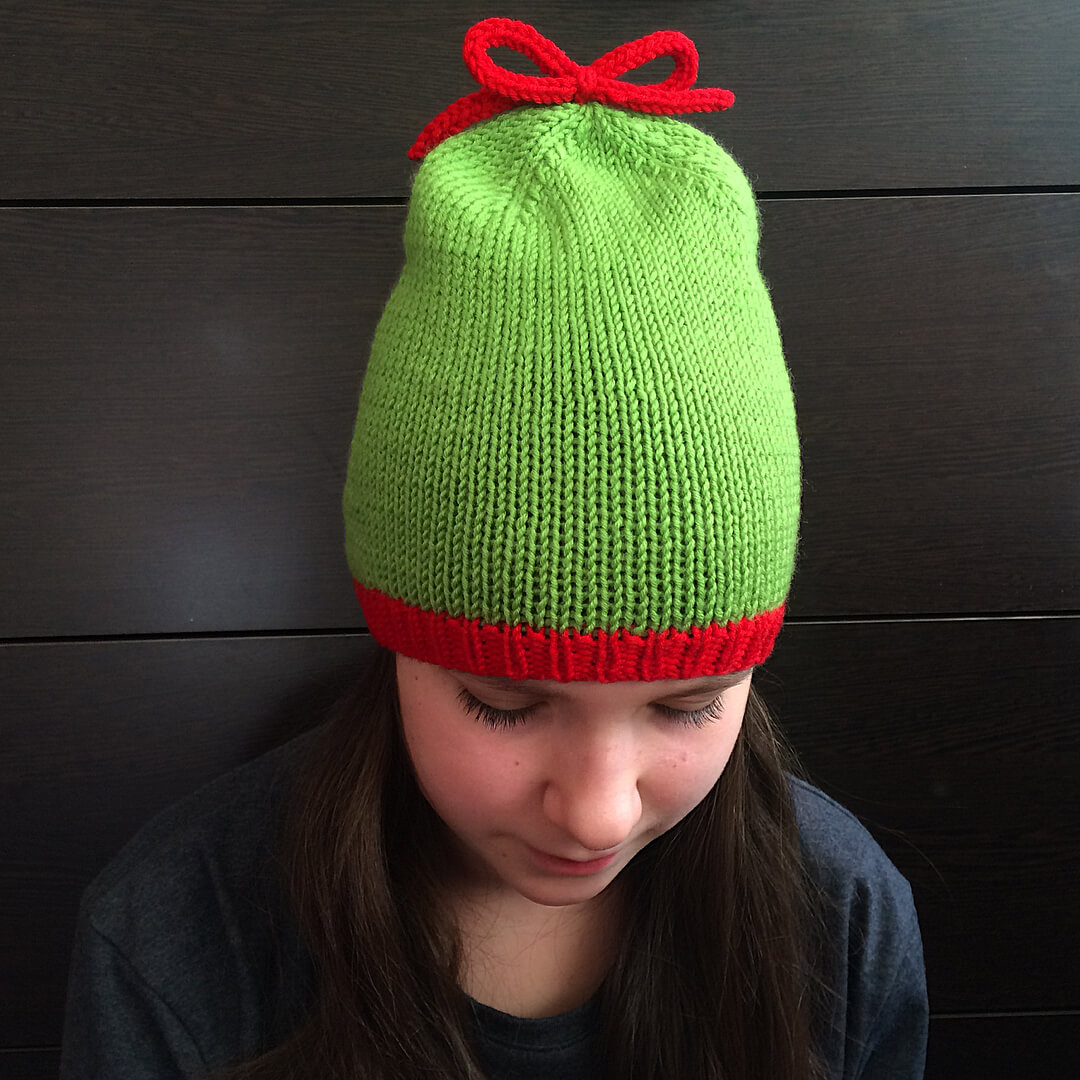 Салатовая шапка-бини с красной резинкой на голове, вид сверху